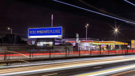 An image of a roadside billboard showing the artwork ‘More Immigrants Please’ (2023) by Osman Yousefzada